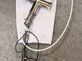 a silver spray gun on the ground next to a white bag