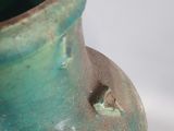 a green vase that is sitting on a white surface