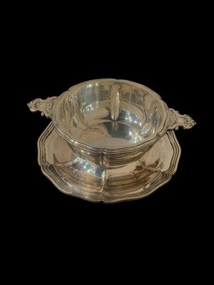 un service en argent ancien composé d'un bol et d'une soucoupe, sur fond noir