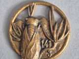an image of a gold insect pendant on a white surface