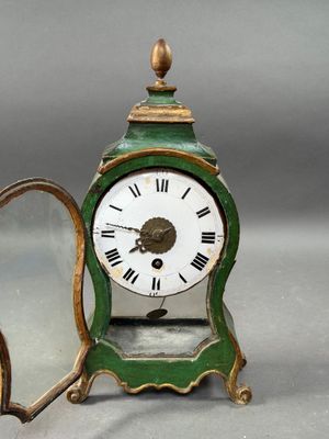 a small green clock with roman numerals on it