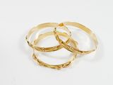 un ensemble de trois bracelets rigides dorés sur fond blanc