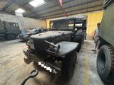 un homme debout à côté d'un véhicule militaire dans un garage