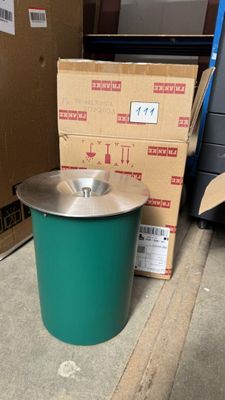 une poubelle verte posée par terre à côté d'un carton