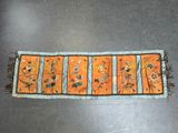 an orange table runner with flowers and birds on it