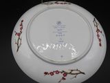 a white plate with red flowers on it on a black background