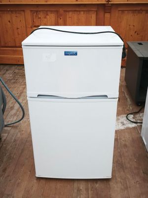 un réfrigérateur blanc posé à même le sol dans une pièce