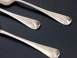 three silver spoons and a spoon on a black surface
