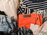 a pile of clothes and a purse sitting on a bed