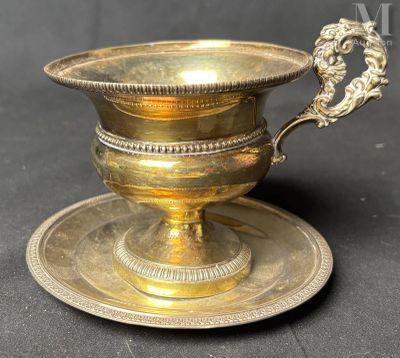 une tasse et une soucoupe en laiton ancien posées sur une assiette à sauce