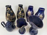 five blue vases with gold designs on them on a white surface