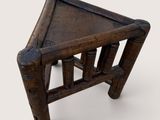 a small wooden stool with a leather seat on it