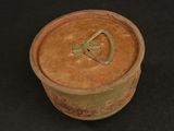 a clay pot with a metal handle on a black surface