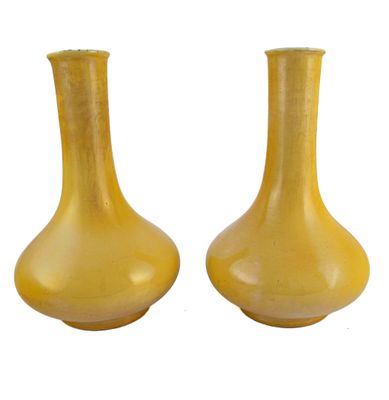 une paire de vases jaunes posés sur une surface blanche, sur fond blanc
