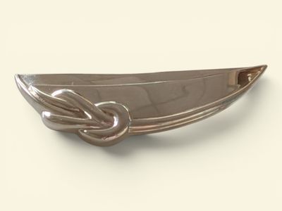 une assiette en argent ornée d'un nœud sur un fond blanc
