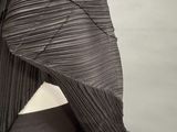 the back of a woman ' s black dress with pleas on it
