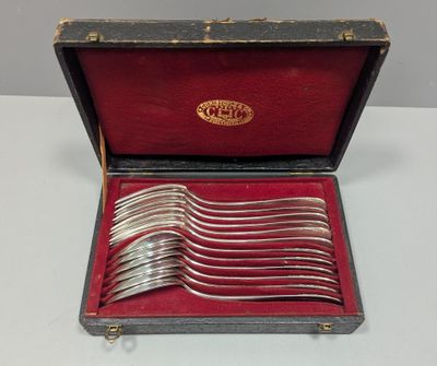 des couverts dans un coffret à doublure rouge, posés sur une table