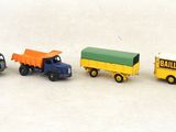 quatre camions miniatures posés les uns à côté des autres sur une surface blanche