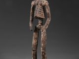 une figurine en bois représentant un homme avec un crâne sur la tête
