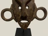 an image of a wooden mask on a stand on a white background