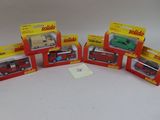 six véhicules miniatures assortis, emballés dans leurs boîtes, posés sur une surface blanche