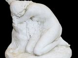 une statue blanche représentant une femme assise sur un rocher