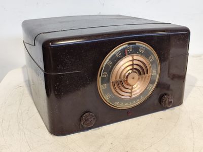 une radio noire posée sur une table, sur fond blanc