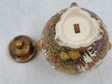 a small vase with a lid and a bell on a table
