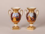 deux vases sur lesquels sont peints des personnages, posés sur une table
