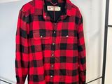 une chemise à carreaux rouges et noirs suspendue à un portant