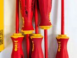 six red and yellow screwdrivers are lined up on a white surface