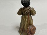 a small statue of a woman with a hat and a bag
