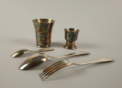 un service d'argenterie posé sur une table, comprenant une tasse et une cuillère en argent