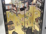 un paravent oriental orné d'une peinture représentant des personnes dans une cour