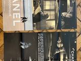 deux brochures Chanel posées sur un parquet, avec une photo en noir et blanc d'une femme