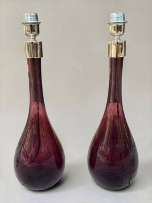 une paire de lampes en verre rouge avec des finitions en laiton, posées sur une surface blanche