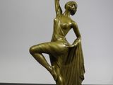 une statue en bronze représentant une danseuse, posée sur un socle en marbre
