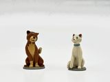 deux figurines de chats assis l'un à côté de l'autre sur une surface blanche