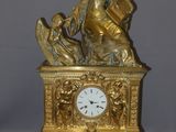 a gold clock with a statue of a woman holding a book