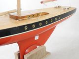 une maquette de bateau posée sur un socle, sur une surface blanche