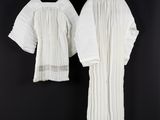 two white dresses hanging on a clothes rack in front of a black wall