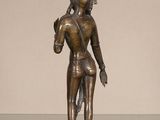 bronze statue of a person holding a bird on a table