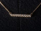 a gold necklace with a row of diamonds on it