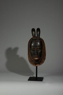 une image représentant un masque en bois posé sur un socle, sur fond blanc