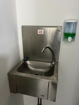 a stainless steel sink in the corner of a bathroom