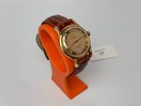 une image représentant une montre-bracelet avec un bracelet orange sur un fond blanc