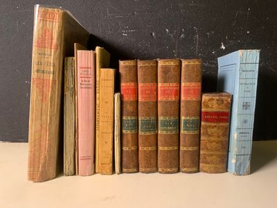 de nombreux livres anciens alignés sur une étagère près d'un mur noir