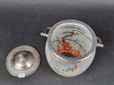 a silver container with a flower design on it and a silver lid