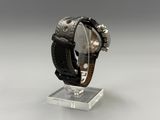 wrist watch with black leather band and silver face on a clear stand