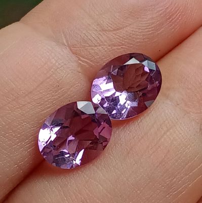 une paire de saphirs roses à la main de quelqu'un
